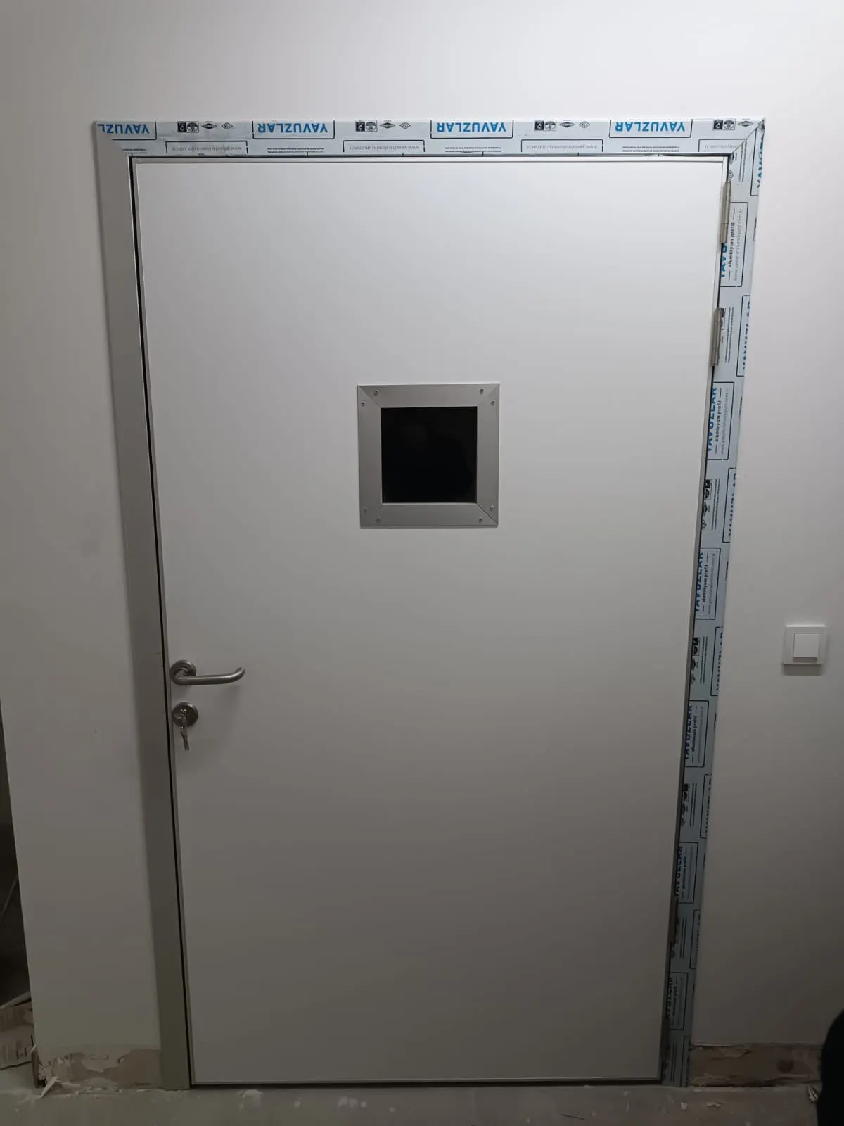 Koruma bantlı gözetleme pencereli kurşun kapının montaj sonrası hâli